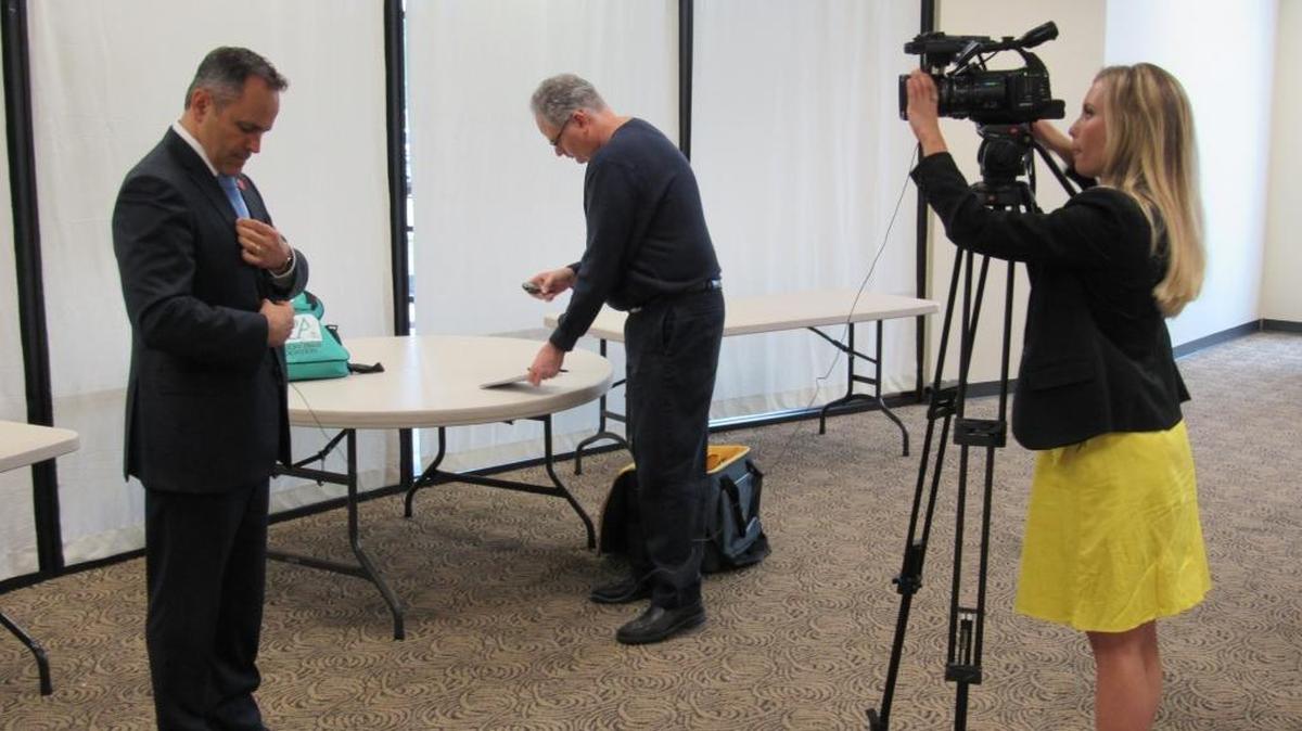Gov. Matt Bevin, left, attaches a microphone to his jacket while preparing to be interviewed by Dean Manning, center, a reporter for the News Journal newspaper in Corbin, and Lauren Osborne, who is with WYMT television in Hazard, after Bevin spoke at a regional prayer breakfast in Corbin on April 24, 2017.