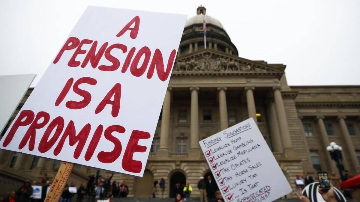 Demonstrators hold signs during a rally against the Republican proposal to reform the state's pension system outside of the Capitol in Frankfort, Ky., Wednesday, Nov. 1, 2017.