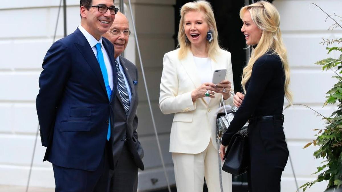 Treasury Secretary Steven Mnuchin, left, and his wife, Scottish actress Louise Linton, right, and Secretary of Commerce Wilbur Ross, second from left, and his wife Hilary Geary, second from right, wait for President Donald Trump on the South Portico of the White House Washington, Saturday, July 29, 2017.