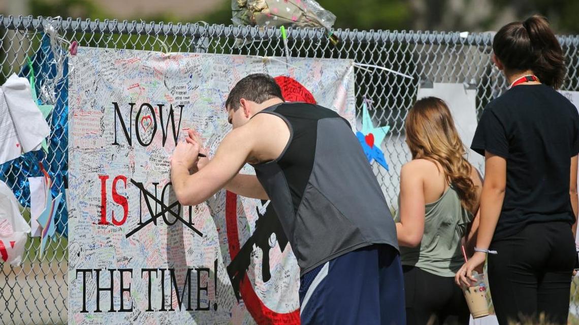 A man signed a banner as people paid tribute at a memorial for the victims of the shooting at Marjory Stoneman Douglas High School on Sunday in Parkland, Fla. The Feb. 14 attack on the school by a former student killed 17.