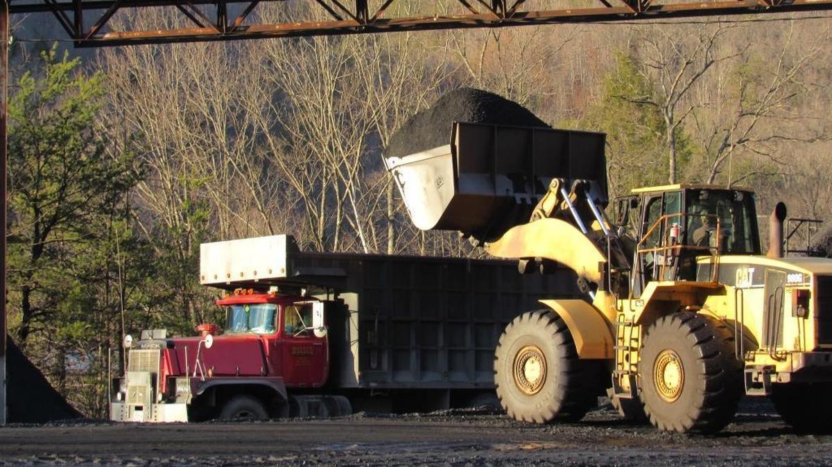 A worker uses a large front-end loader to scoop coal from a pile near where it was mined in Harlan County and puts it into a truck to be taken to a rail-loading facility.