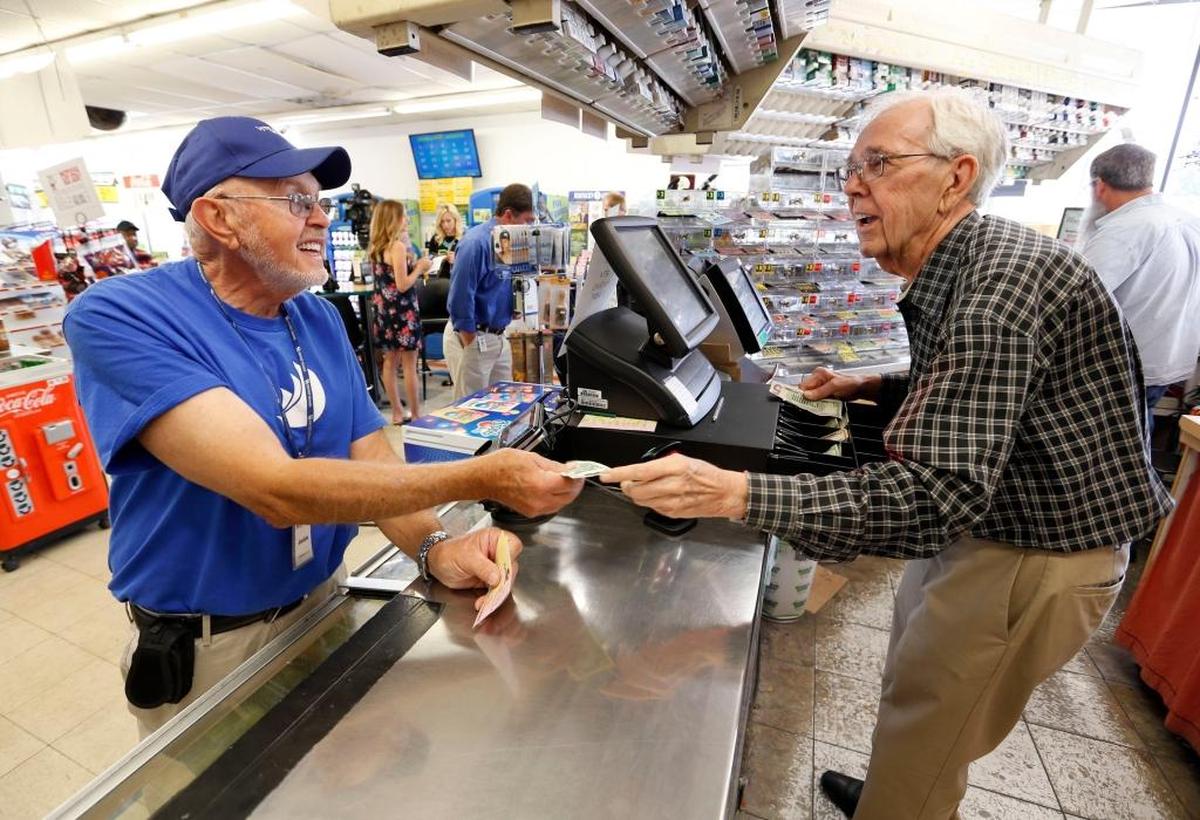 In this 2017 file photo, Jackie Rogers, left, bought a Powerball ticket from owner Eddie White at the Dairy Mart, 155 East Reynolds Rd. in Lexington. When there were big jackpots, players would wait in line to buy tickets at this particular store.