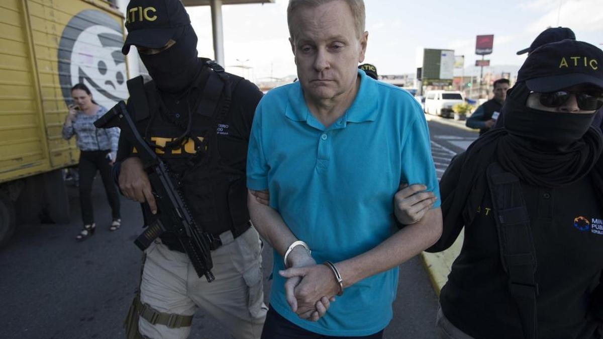 Honduran agents escorted Eric Conn, center, to his extradition flight Dec. 5 at the Toncontin International Airport in Tegucigalpa, Honduras. He was captured as he came out of a restaurant in the coastal city of La Ceiba.