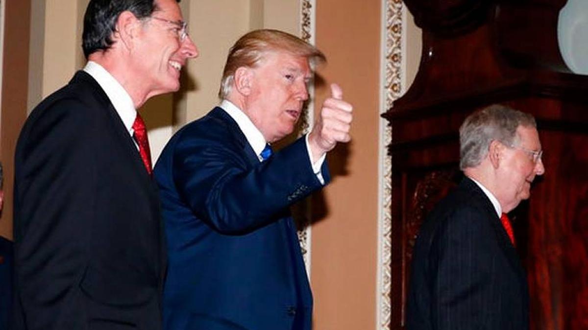 President Donald Trump gives thumbs up as he walks with Senate Majority Leader Mitch McConnell of Kentucky, right, and Sen. John Barrasso, R-Wyo., as he arrives to meet with Senate Republicans on Capitol Hill, Tuesday, Nov. 28, 2017, in Washington.