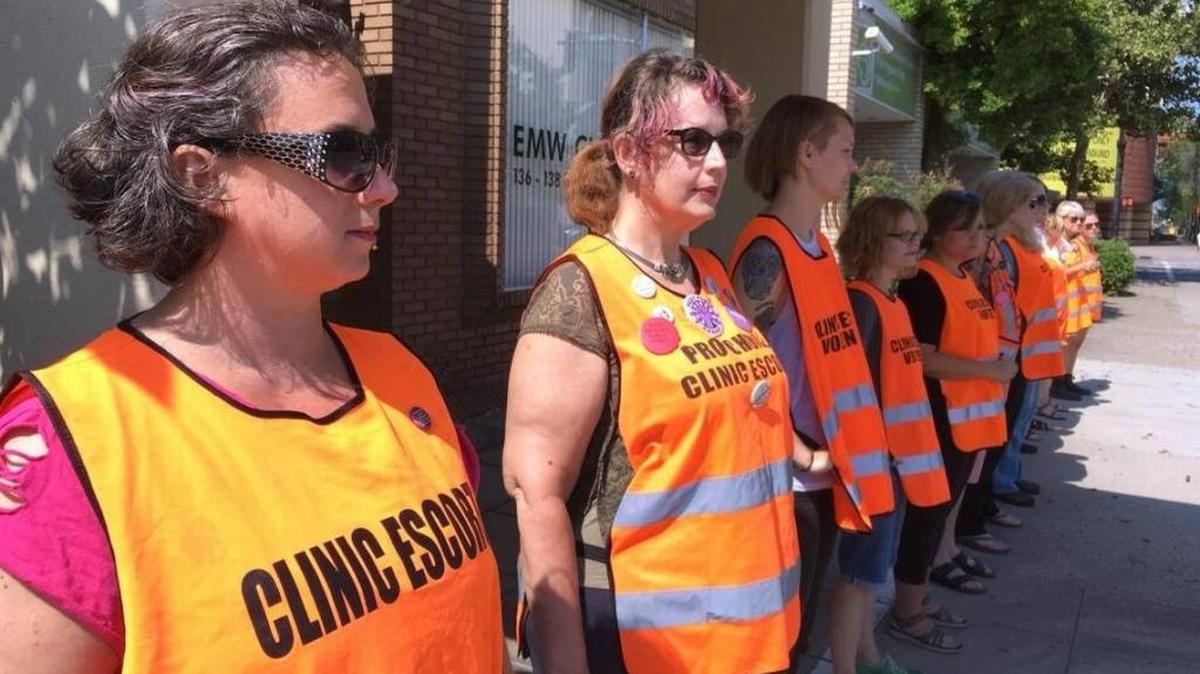 Meg Stern, left, and other escort volunteers lined up outside the EMW Women’s Surgical Center in Louisville on July 17. The escorts were preparing for a large anti-abortion protest seeking to shut down the center, the last one providing abortions in the state of Kentucky.