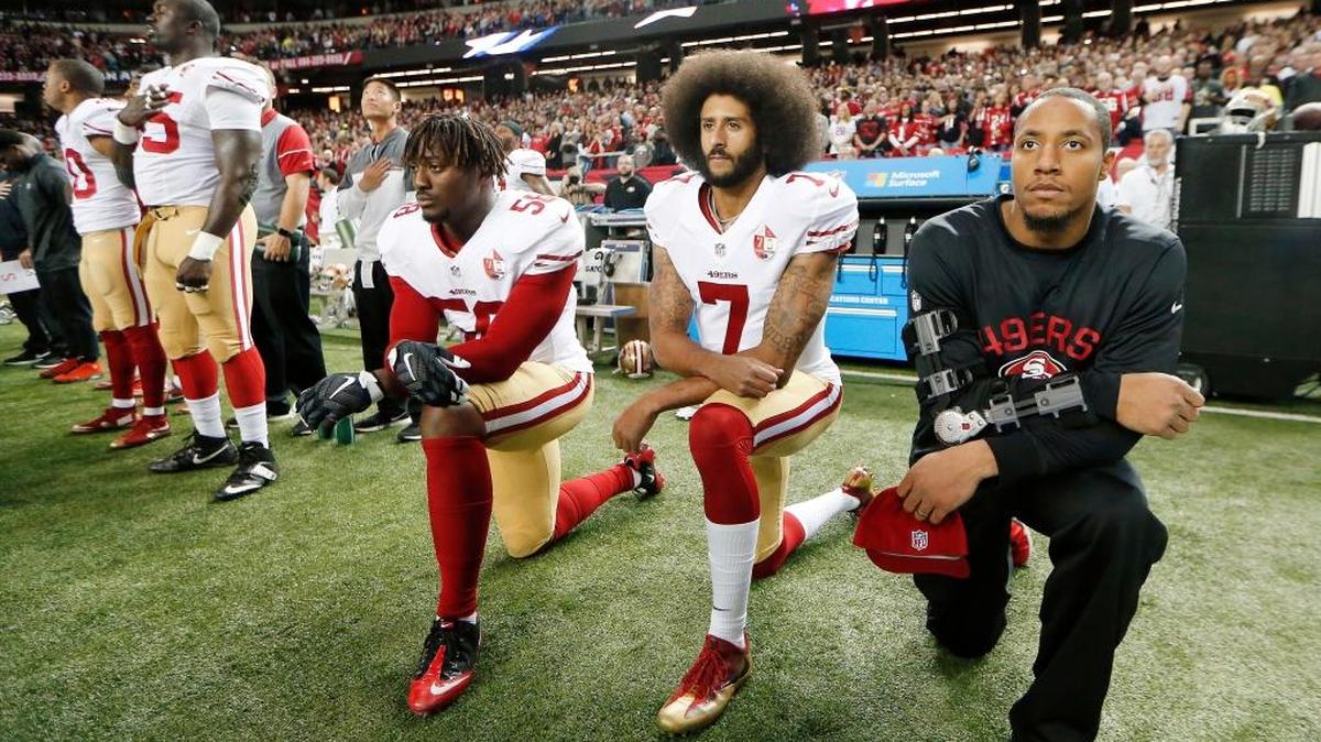 Former San Francisco 49ers quarterback Colin Kaepernick, center, has been kneeling during the National Anthem to protest police brutality against minorities.