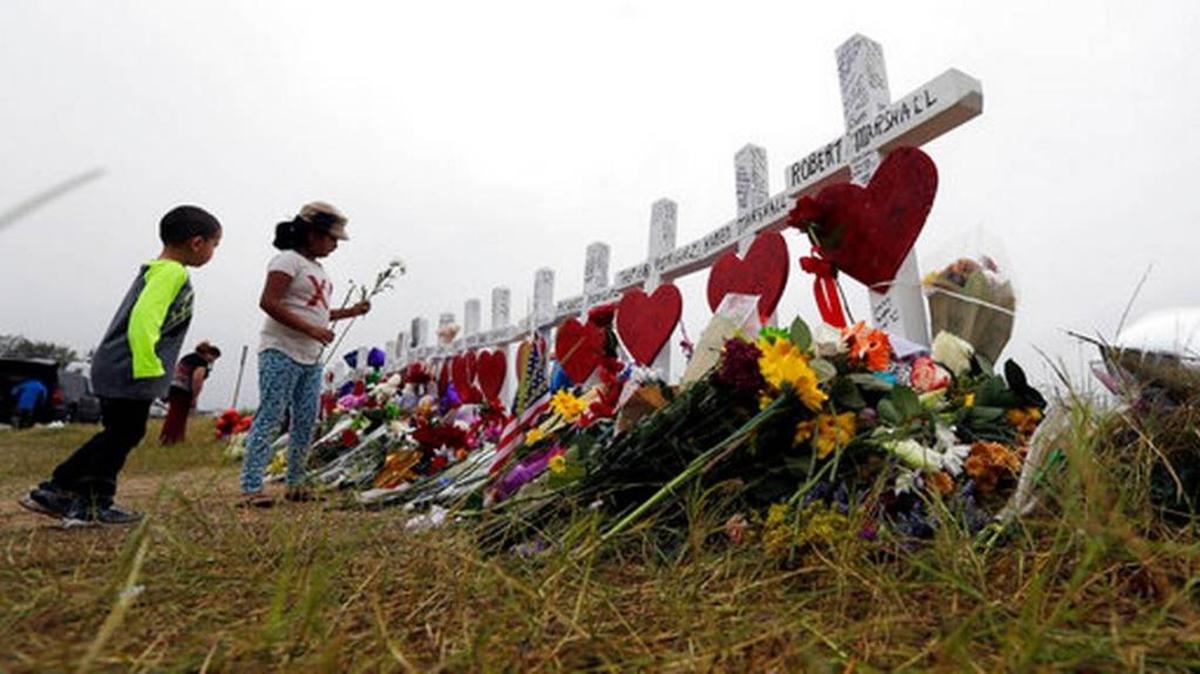 Alexander Osborn and Bella Araiza leave flowers at a makeshift memorial for the victims of the shooting at Sutherland Springs Baptist Church, Sunday, Nov. 12, 2017, in Sutherland Springs, Texas. A man opened fire inside the church in the small South Texas community, killing more than two dozen.