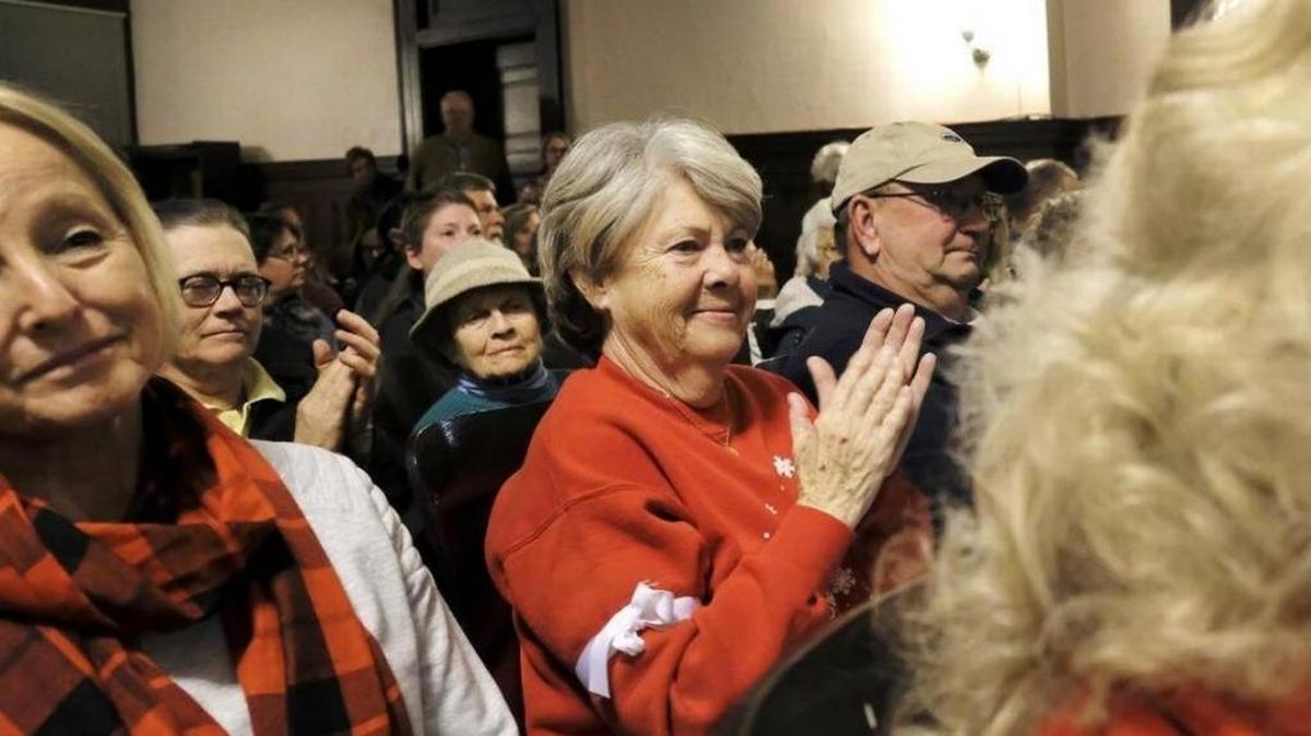 People who crowded into the Bourbon County Circuit Court room to oppose expansion of Bluegrass Station applaud as Fiscal Court members rejected the plan. Some wore white armbands symbolizing their opposition to the project.