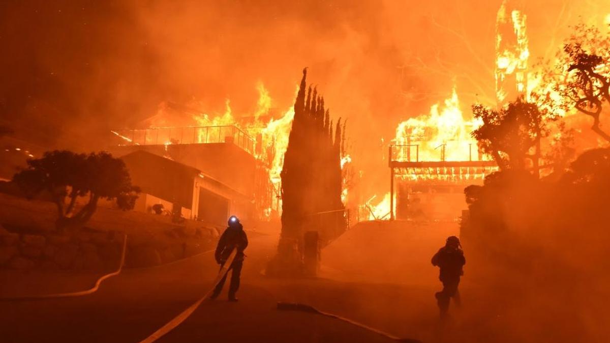 In this photo provided by the Ventura County Fire Department, firefighters work to put out a blaze burning homes early Tuesday. Authorities said the blaze broke out Monday and grew wildly, consuming vegetation that hasn't burned in decades.