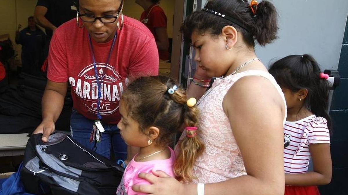 Madlyn Lopez and her litte sister, Yaretzi Rathesc, received backpacks filled with school supplies from volunteer Kim Mayes at the YMCA backpack drive in 2016.