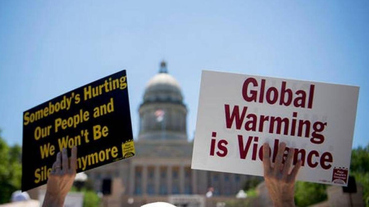 A protester holds signs during a protest organized by Kentucky Poor People's Campaign in Frankfort on June 4.