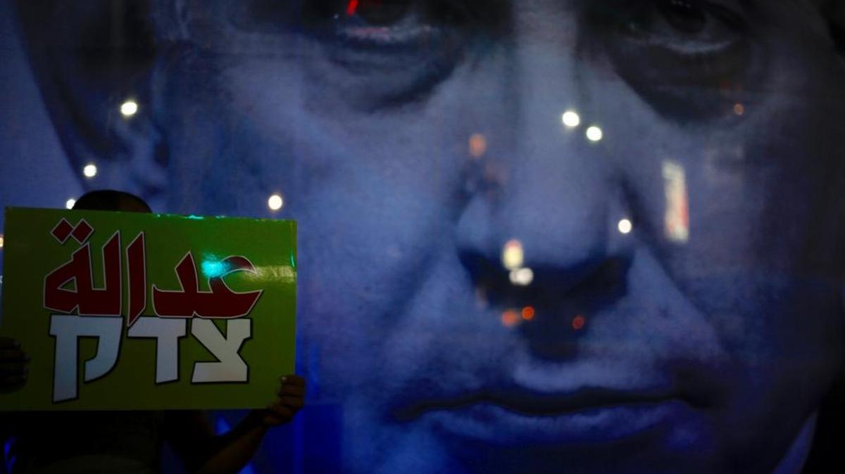 A man held a sign that reads “Justice” in front of a poster showing Israeli Prime Minister Benjamin Netanyahu during an Aug. 11 protest against the Jewish nation bill in Tel Aviv, Israel. The recently passed law enshrines Israel’s Jewish character and downgrades the standing of Arabic from an official to a “special” language.