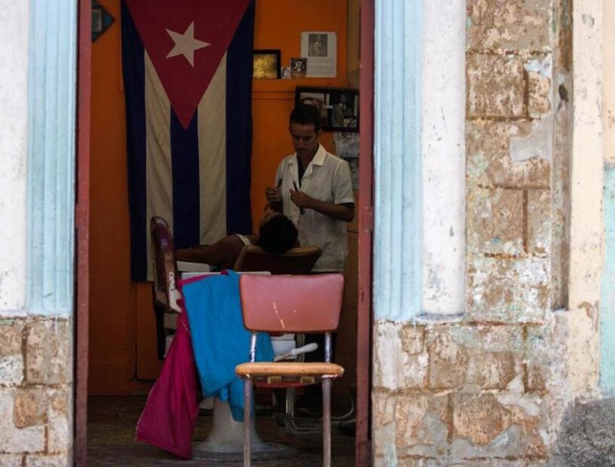 A barber shaves a client at his privately licensed shop in Havana, Cuba, Tuesday, July 10, 2018. The Cuban government will allow new restaurants, bed-and-breakfasts and transportation businesses by the end of the year 2018, reopening the most vibrant sectors of the private economy after freezing growth for more than a year. (AP Photo/Desmond Boylan)