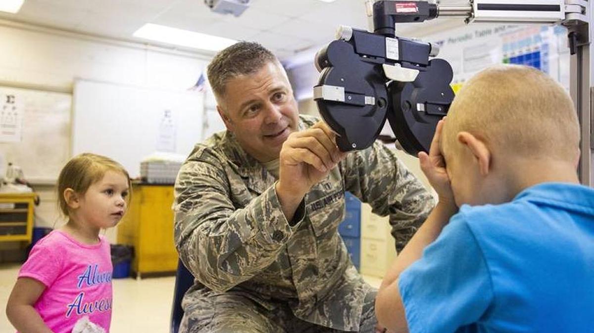 Major Brett Ringger set up to examine Isaac Dunn, 9, of Morgan County while his sister Mercedes Dunn, 3, watched at the Lee County High School in June. Health services were offered as part of a military training mission to practice medical set up for times of emergency, conflict or disaster.