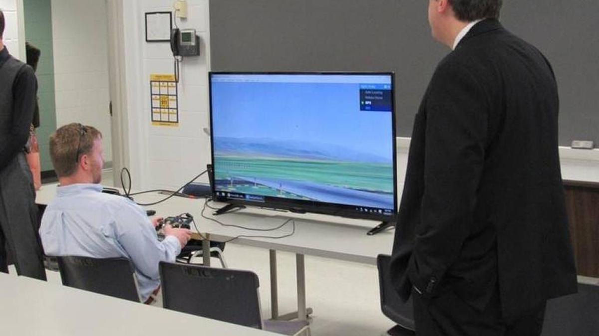Knott County Judge-Executive Zach Combs Weinberg, seated, used a drone simulator April 24 at Hazard Community and Technical College. Perry County Judge-Executive Scott Alexander is at right. They took part in announcing a plan to build a drone-testing site in the area.