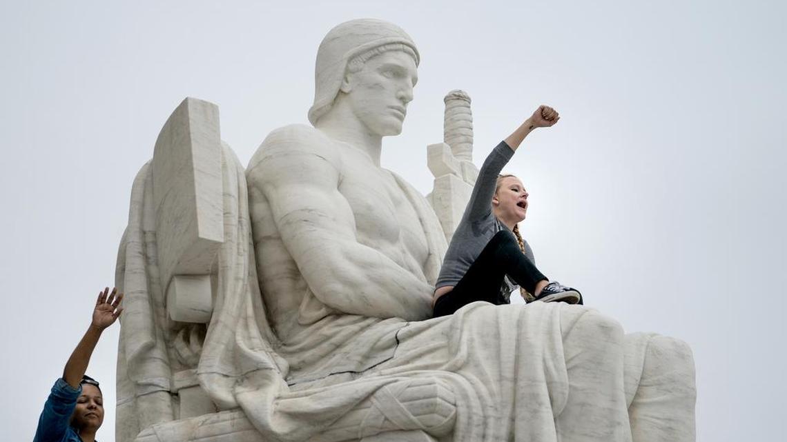 Demonstrators on the Authority of Law statue during a protest outside the Supreme Court building after Judge Brett Kavanaugh was confirmed to the court.