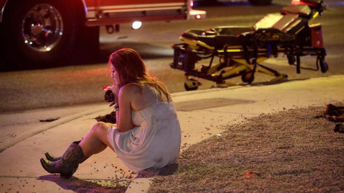 A woman sat on a curb at the scene of a shooting outside of a music festival along the Las Vegas Strip on Monday. At least 58 people were killed and at least 515 injured by Stephen Craig Paddock, 64, who lived in Nevada. Police said he killed himself.