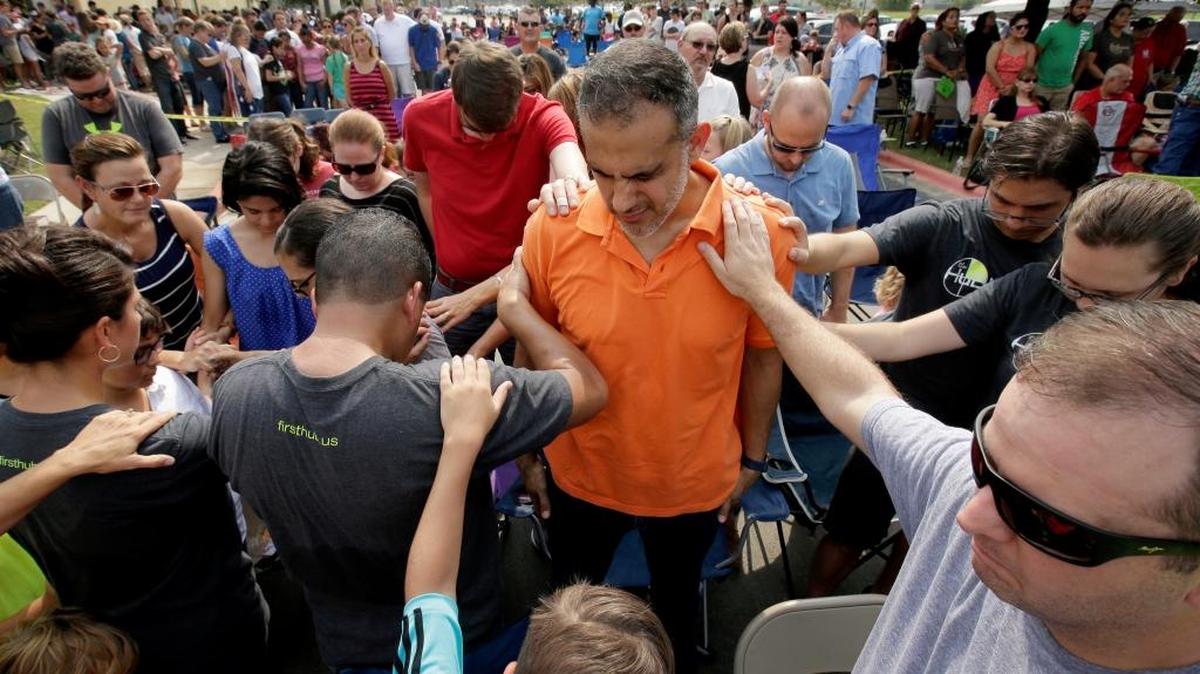 Church members gathered Sept. 3 to pray around flood victim Carlos Ochoa during Sunday service in the parking lot of the First Baptist Church in Humble, Texas. The church building was flooded with two feet of water from Hurricane Harvey.