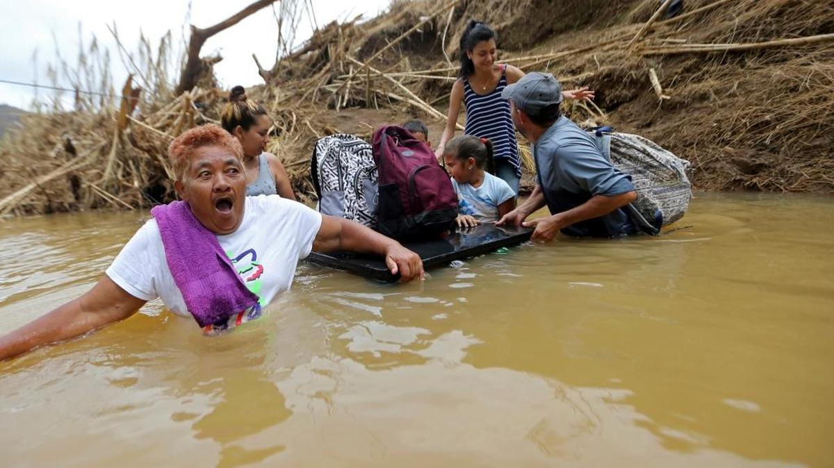 Marta Sostre Vazquez reacted Wednesday as she waded into a river with her family in Morovis, Puerto Rico, after a bridge was swept away by Hurricane Maria.