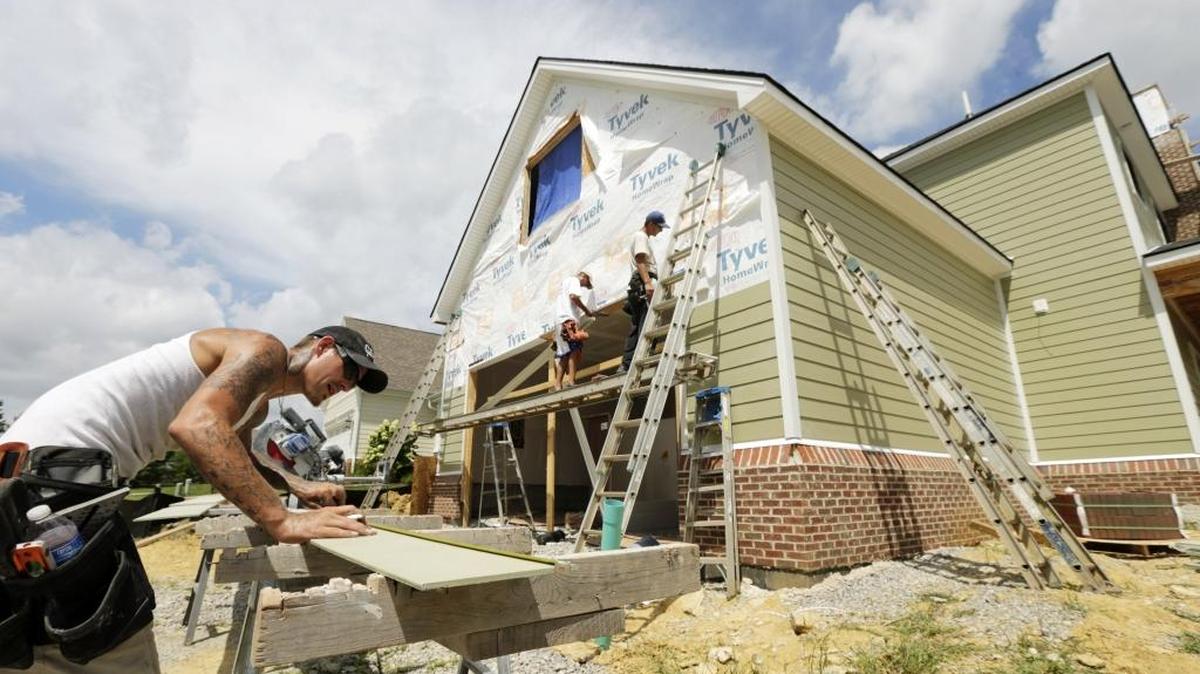 Bobby Noble, left, cut fiber-cement boards for co-workers, Brad Lovelace, left and Les Hanshaw of Custom Home Exterior Inc. as they installed siding on Goodpaster Way in the Patchen Wilkes development in Lexington, Ky, on Aug. 24, 2016.
