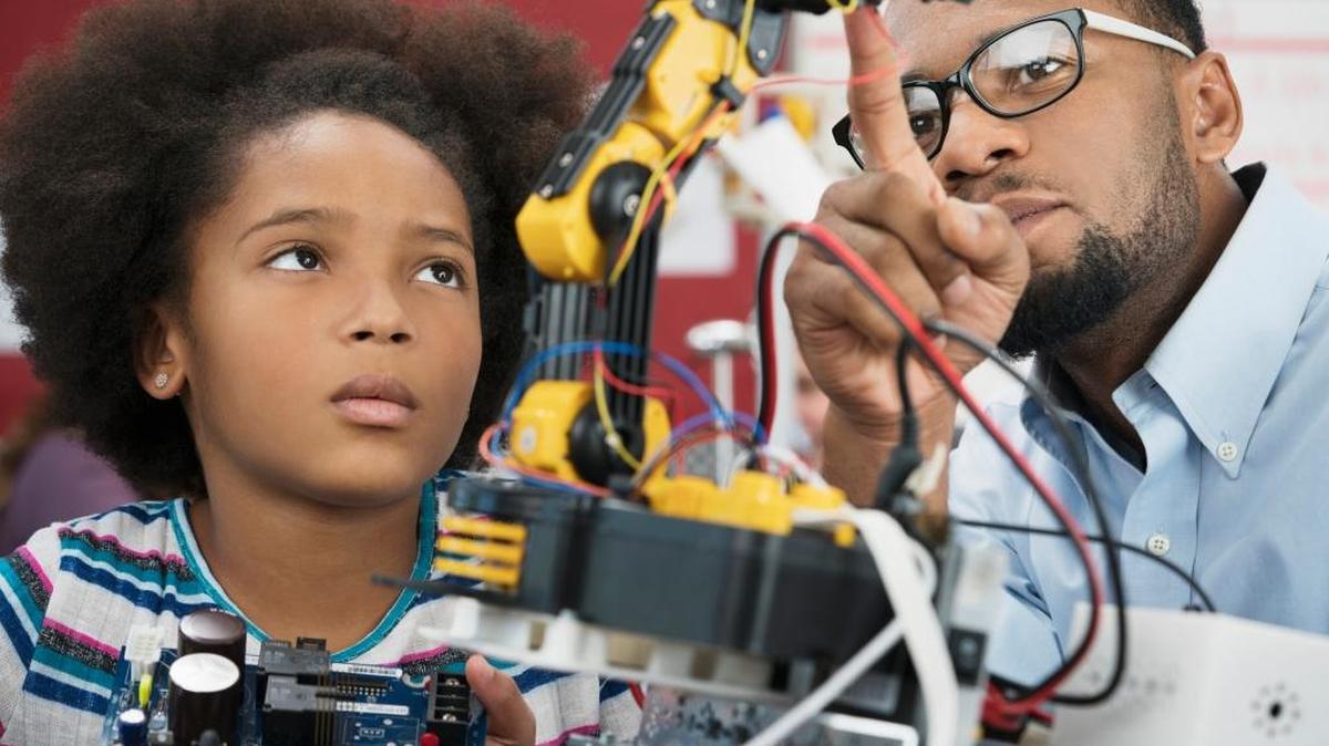 Black teacher helping student with robotics
