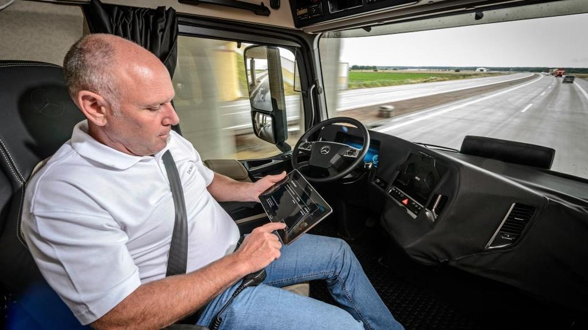 A driver performs other duties while Daimler’s autonomous truck drives itself.