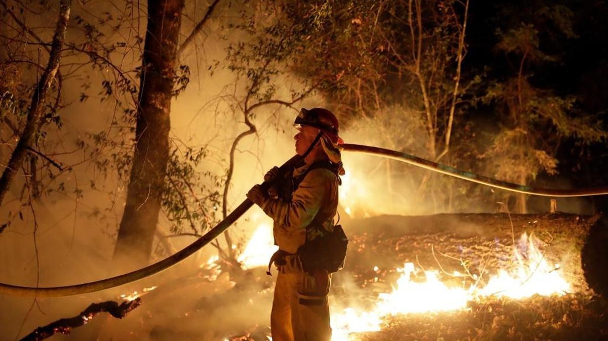 A firefighter held a water hose Oct. 14 while fighting a wildfire, in Santa Rosa, Calif. State officials report that at least 8,900 structures were destroyed and 42 people killed.