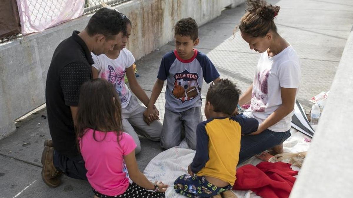 Helen Rodriguez Agurcia, 29, an asylum seeker from Honduras, prays with her husband and four children while waiting on the Mexican side of the Brownsville & Matamoros International Bridge near Brownsville, Texas, June 26, 2018. (Tamir Kalifa/The New York Times)