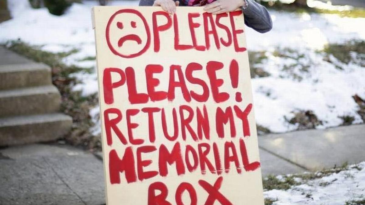 Nicole Breazeale stood by the sign appealing for the return of a memorial of books, bumper stickers for her late husband.