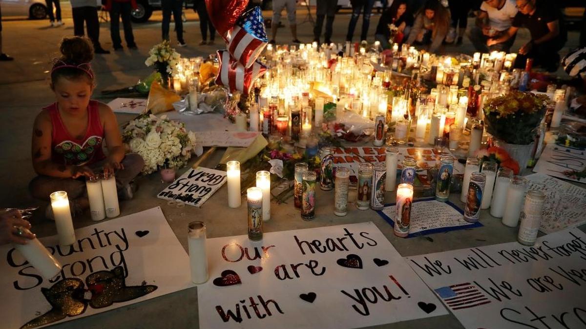 A girl placed candles at a memorial for victims of the mass shooting Tuesday in Las Vegas. A gunman opened fire Sunday on an outdoor music concert in Las Vegas. It was the deadliest mass shooting in modern U.S. history, with at least 59 people killed and hundreds injured — some by gunfire, some during the chaotic escape.