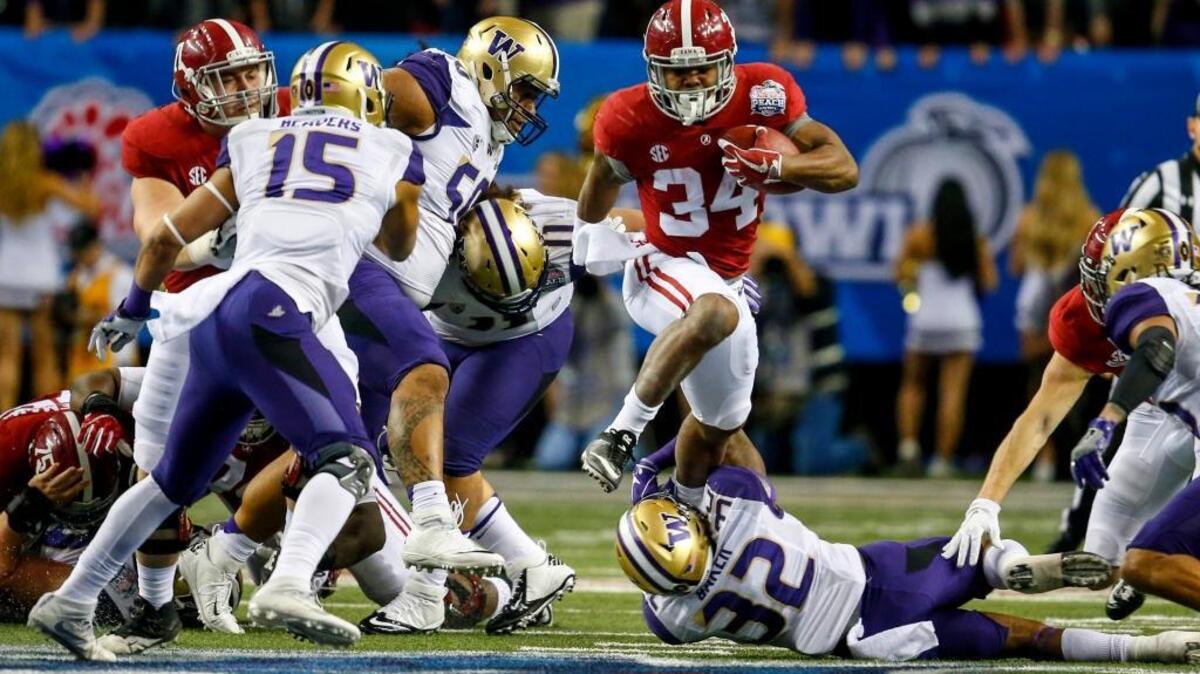 Alabama running back Damien Harris (34) hurdled Washington defensive back Budda Baker (32) as he carried the ball during the first half of the Peach Bowl last season in Atlanta.