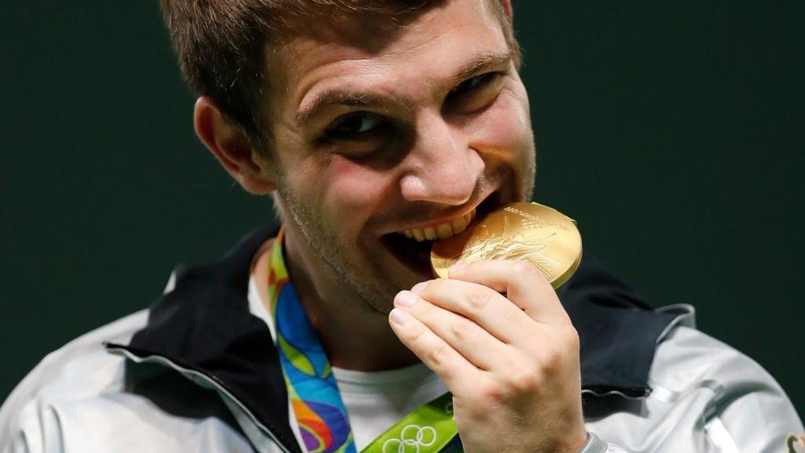 Henri Junghänel of Germany bites his gold medal during the award ceremony for men's 50-meter rifle prone finals, at the Olympic Shooting Center at the 2016 Summer Olympics in Rio de Janeiro, Brazil, Friday, Aug. 12, 2016.