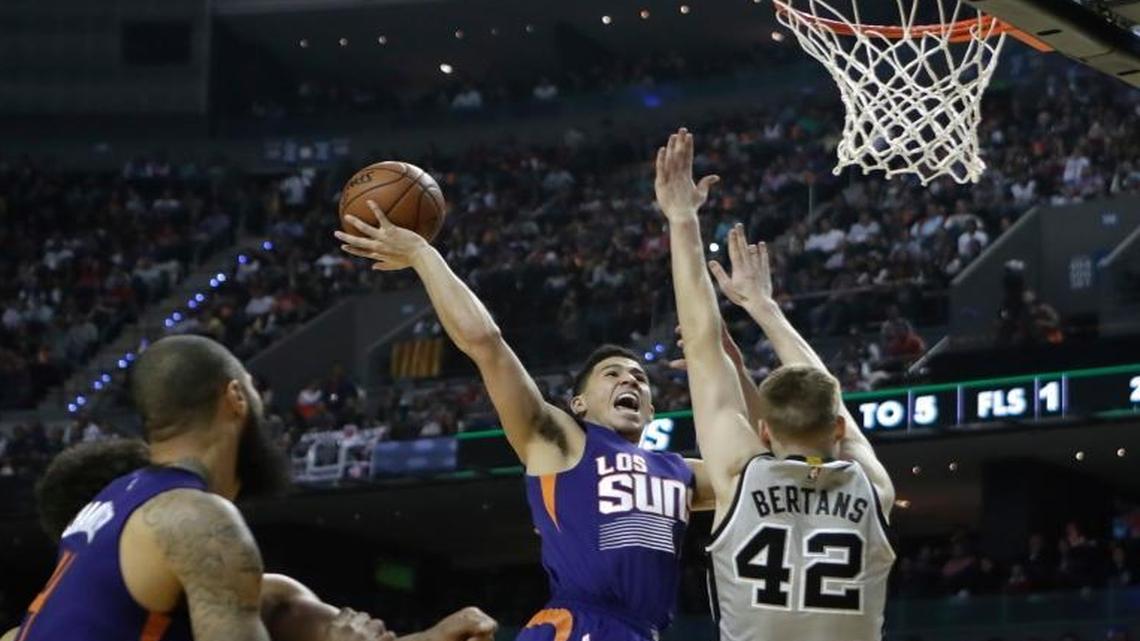 The Phoenix Suns’ Devin Booker, second right, drives for a basket as the San Antonio Spurs’ Davis Bertrans right, attempts to block him, in the first half of their regular-season NBA basketball game in Mexico City, Saturday, Jan. 14, 2017.