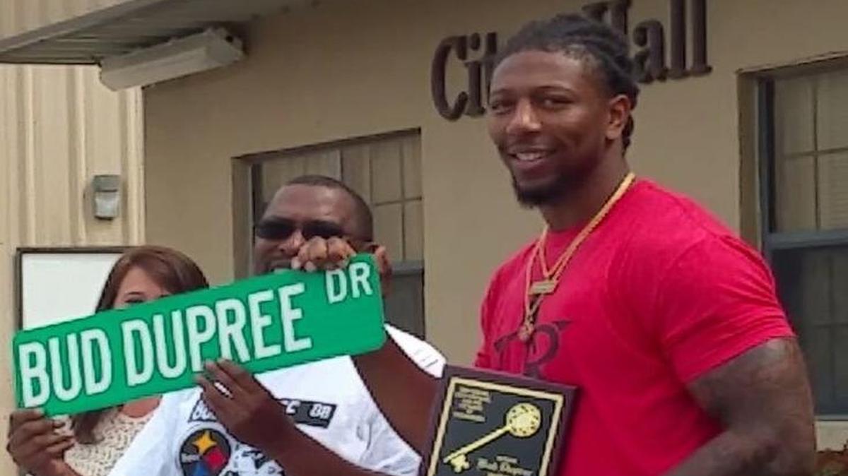 Bud Dupree, right, helps hold up a version of the street sign.