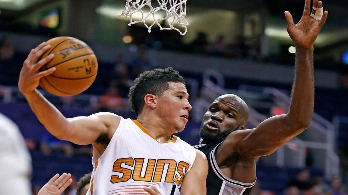 The Phoenix Suns' Devin Booker, left, looks to pass the ball against San Antonio Spurs' Joel Anthony during the second half of an NBA preseason basketball game Monday, Oct. 3, 2016, in Phoenix. The Suns won 91-86.