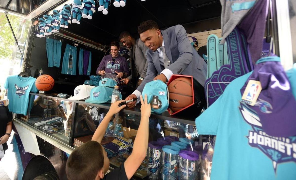 Charlotte Hornets draft picks Malik Monk, center, hands an autographed hat back to a fan as Dwayne Bacon, rear, laughs with a team staff member while greeting fans in uptown Charlotte on Friday, June 23, 2017.