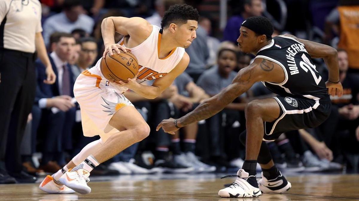 Phoenix Suns guard Devin Booker (1) dribbles around Brooklyn Nets forward Rondae Hollis-Jefferson (24) during the first half of an NBA basketball game Saturday, Nov. 12, 2016, in Phoenix.