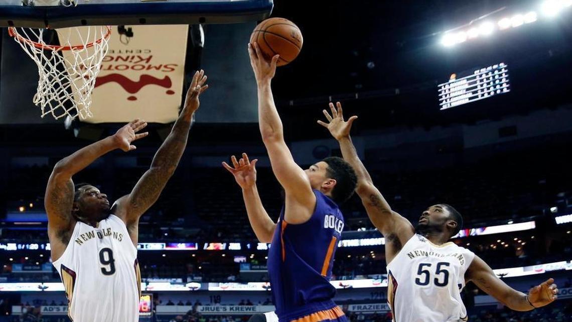 Phoenix Suns guard Devin Booker (1) goes to the basket between New Orleans Pelicans forward Terrence Jones (9) and guard E'Twaun Moore (55) during the first half of an NBA basketball game in New Orleans, Friday, Nov. 4, 2016.