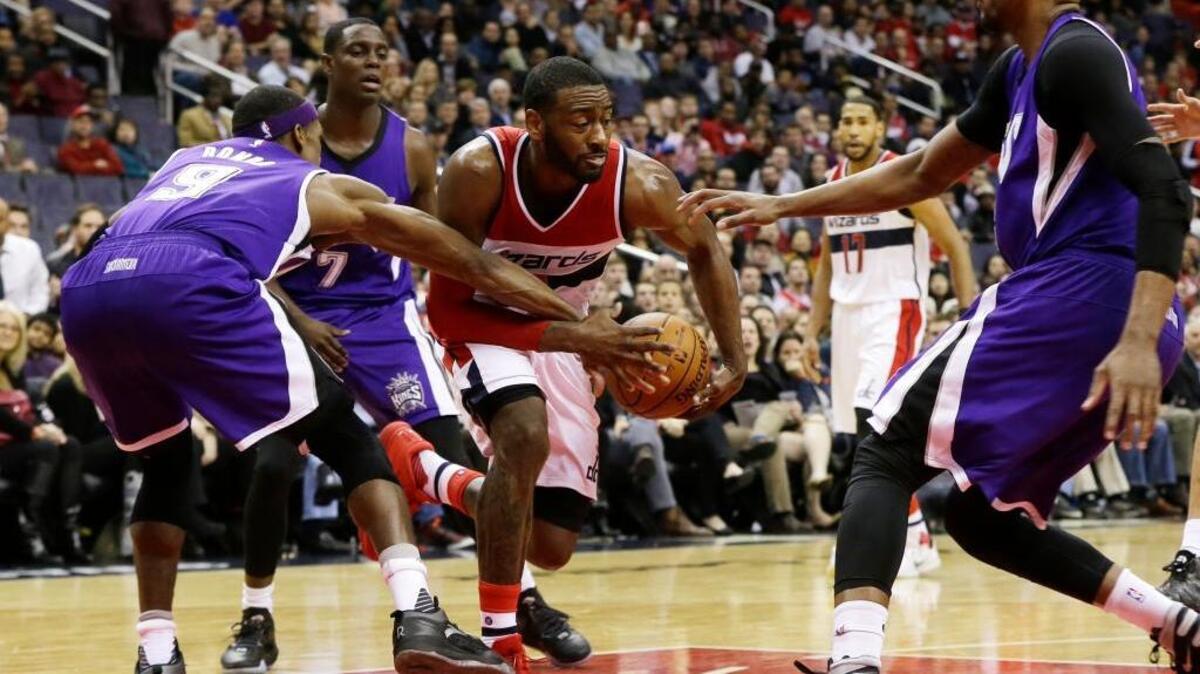 Washington Wizards guard John Wall (2) fights for the ball as he drives through Sacramento Kings guard Rajon Rondo (9), guard Darren Collison (7) and forward Rudy Gay during the second half of an NBA basketball game Monday, Dec. 21, 2015, in Washington. The Wizards won 113-99.
