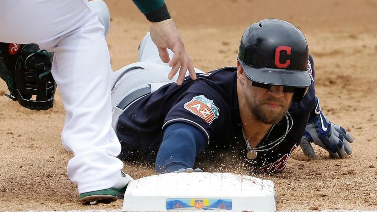 The Cleveland Indians’ Collin Cowgill slid into first base and avoided a pickoff attempt against the Oakland Athletics during the second inning of a spring training game in Mesa, Ariz., on Monday, March 28, 2016.