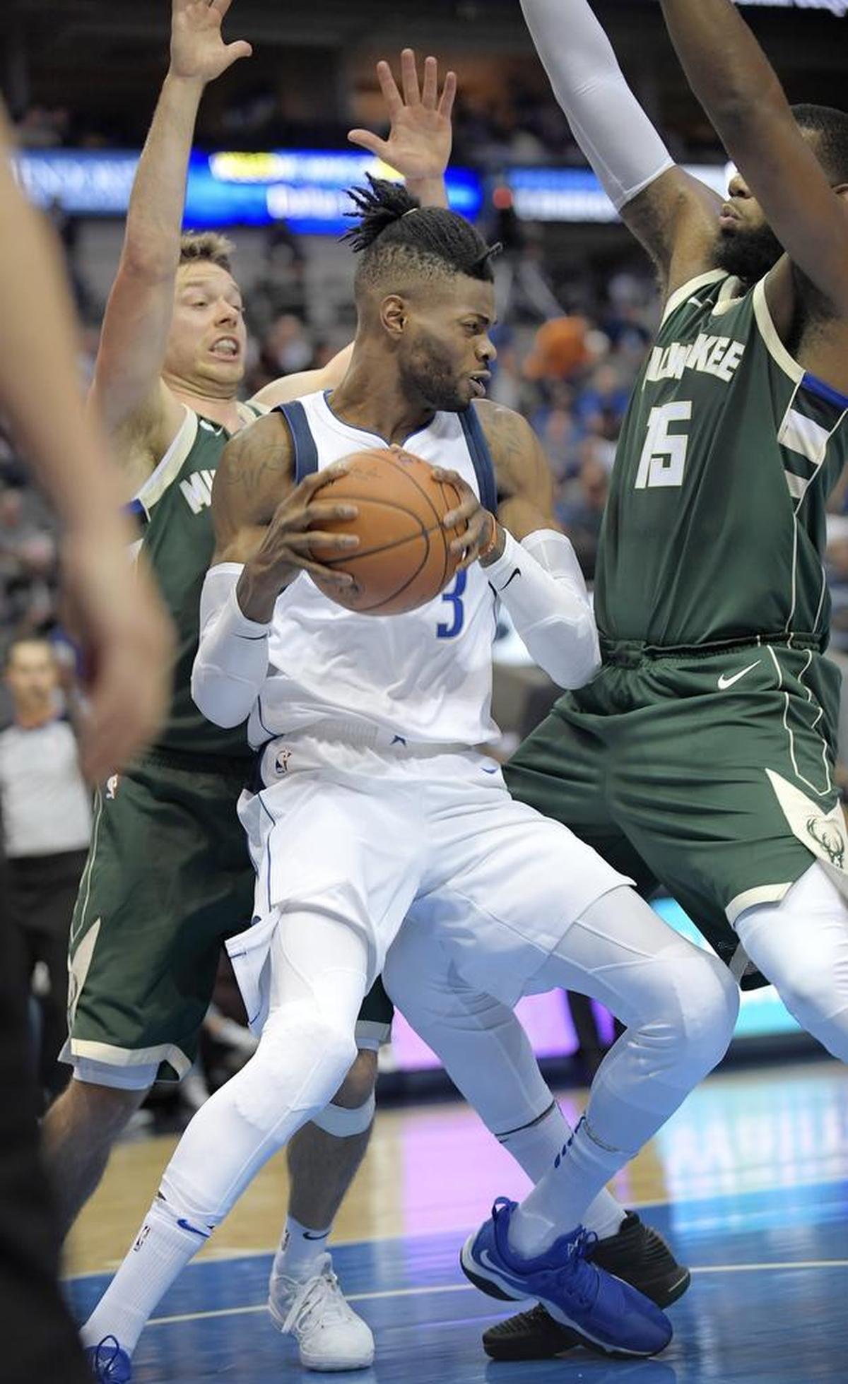 Dallas Mavericks forward Nerlens Noel (3) comes down with a rebound in front of Milwaukee Bucks guard Matthew Dellavedova (8) and center Greg Monroe (15) as the Dallas Mavericks play the Milwaukee Bucks in preseason NBA game Bucks at American Airline Center in Dallas on Oct. 2, 2017.