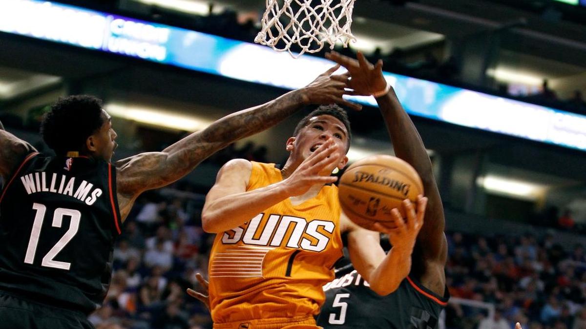 Phoenix Suns guard Devin Booker (1) drives to the basket between Houston Rockets' Lou Williams (12) and Montrezl Harrell during the second half of an NBA basketball game, Sunday, April 2, 2017, in Phoenix. The Rockets defeated the Suns 123-116.