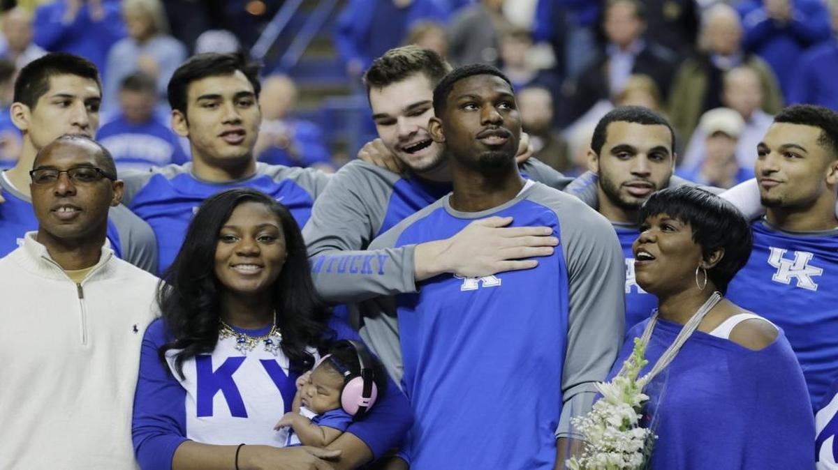 Alex Poythress (22) was hugged by teammate Isaac Humphries while with his family, from left, father Antoine Poythress, sister Alexis (holding her daughter Alivia) and mother Regina Poythress, during Senior Day events before Kentucky’s game against LSU on March 5, 2016.