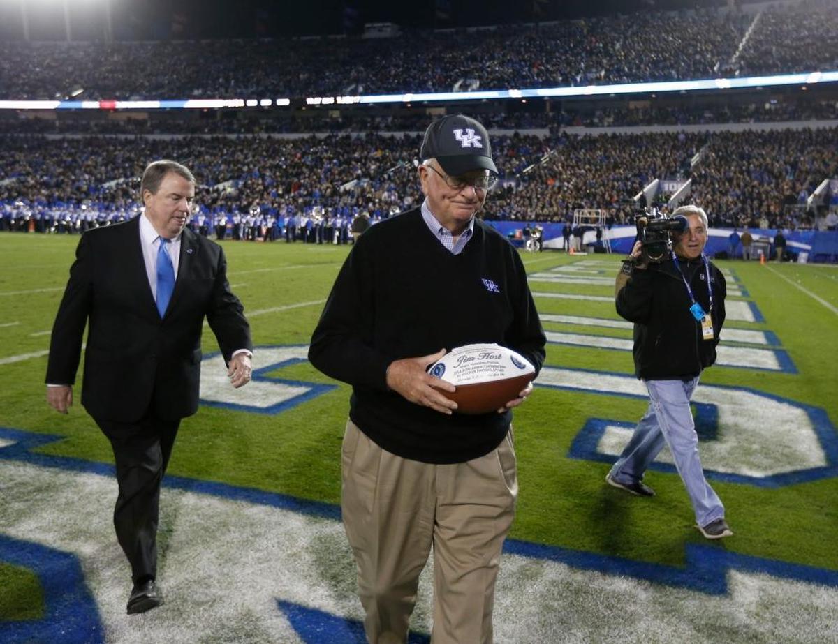 Jim Host, center, walked off the field after he received the 2014 Outstanding Contribution to Amateur Football award from National Football Foundation President Steven Hatchell, left, during halftime of the Kentucky-South Carolina football game.