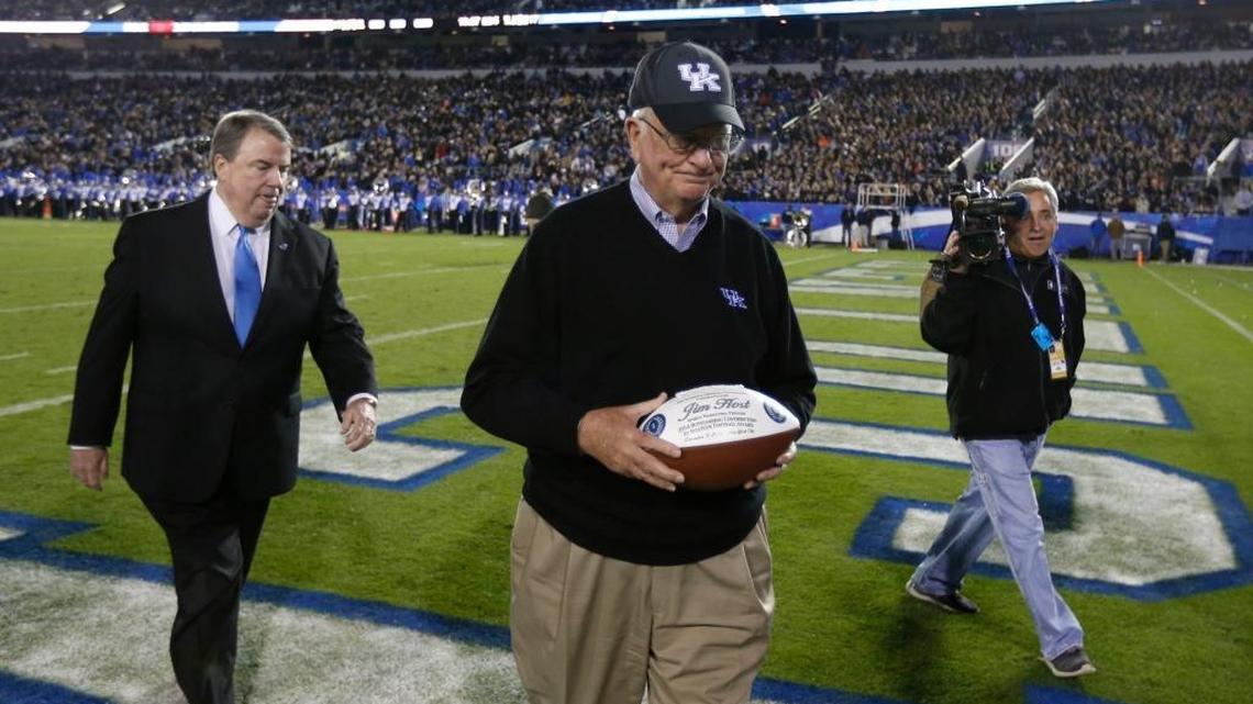 Jim Host, center, walked off the field after he received the 2014 Outstanding Contribution to Amateur Football award from National Football Foundation president Steven Hatchell, left, during halftime of the Kentucky-South Carolina football game at Commonwealth Stadium in Lexington on Oct. 4, 2014.