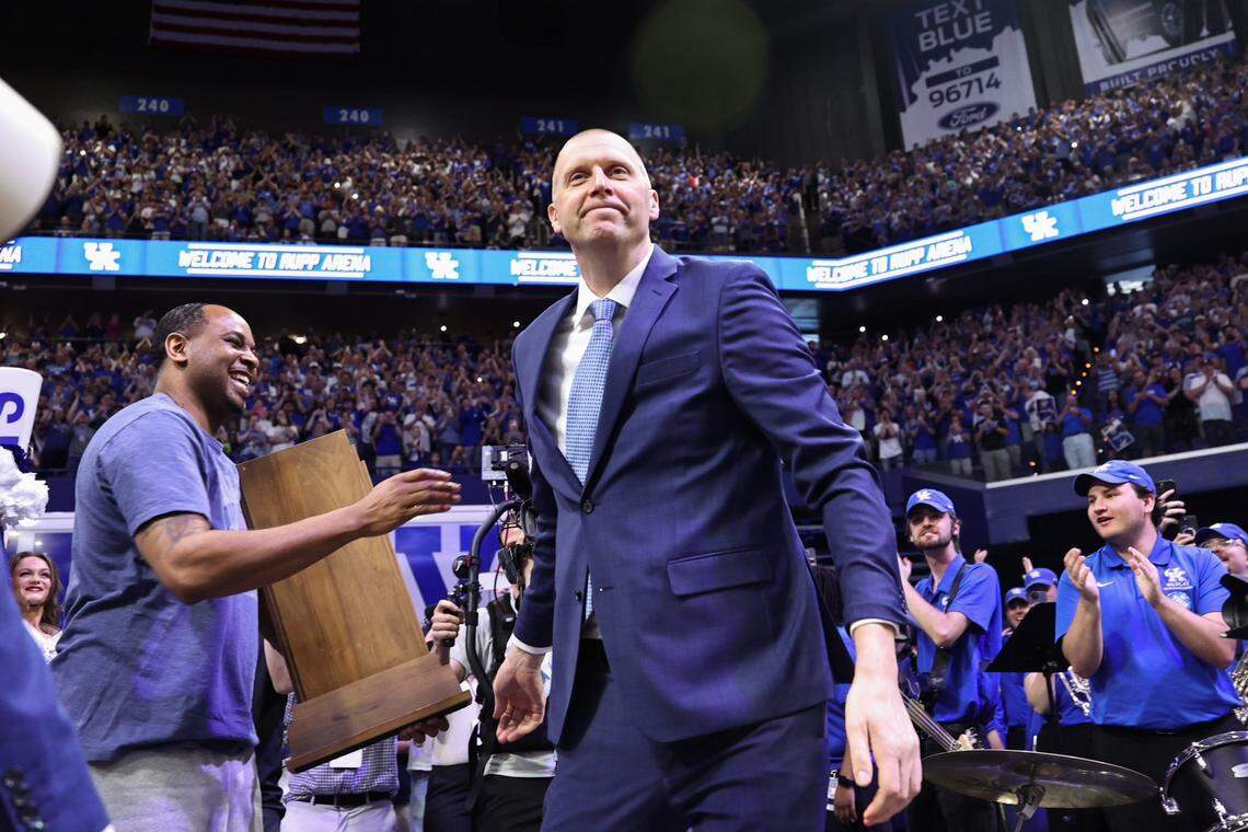 Mark Pope handed the 1996 NCAA championship trophy to former teammate Derek Anderson, left, before he was introduced as Kentucky's basketball coach at Rupp Arena in Lexington on Sunday, April 14, 2024.