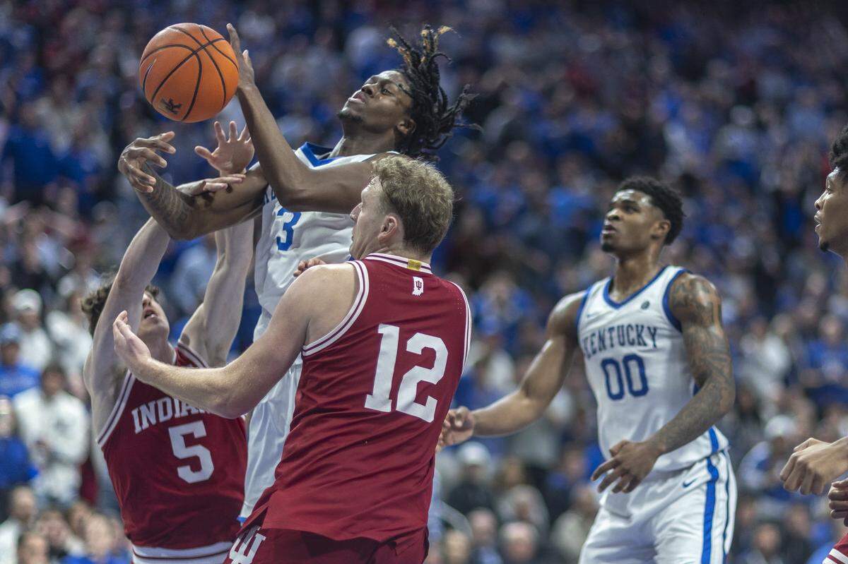 Kentucky guard Kam Williams (3) reaches for a rebound in front of Indiana guard Conor Enright (5) and forward Tucker Devries (12) during a game at Rupp Arena on Dec. 13, 2025. 
