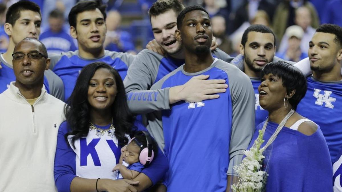 Alex Poythress (22) was hugged by teammate, Kentucky forward Isaac Humphries (15) with family, from left, father Antoine Poythress, sister Alexis holding her daughter Alivia, and his mother Regina Poythress, during Senior Day events before the LSU at Kentucky men's basketball game at Rupp Arena in Lexington, Ky, on March 5, 2016.