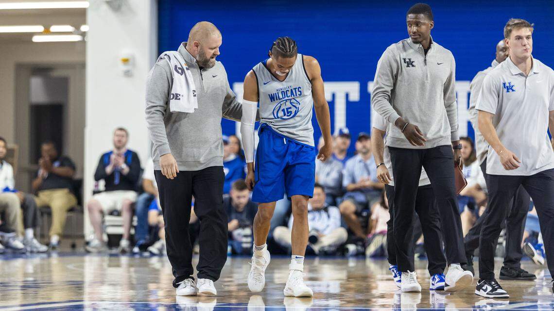 UK senior athletic trainer Brandon Wells, left, helps Jaland Lowe off the court after the Kentucky point guard injured his shoulder during the Blue-White Game on Friday night.
