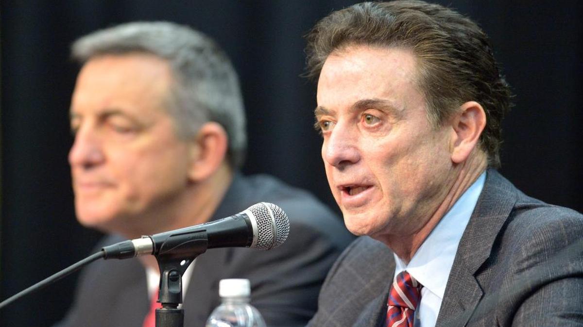 Louisville Coach Rick Pitino, right, addressed the media on Feb. 5 following the school’s announcement of a one-year postseason ban for its men’s basketball team amid ongoing investigations into a sex scandal in which an escort alleged that a former staffer paid her and other dancers to strip and have sex with recruits and players. Behind Pitino is Chuck Smrt, president of the compliance group.